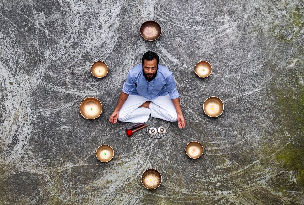 Man meditating surrounded by singing bowls in Pokhara, Nepal, promoting tranquility and mindfulness.