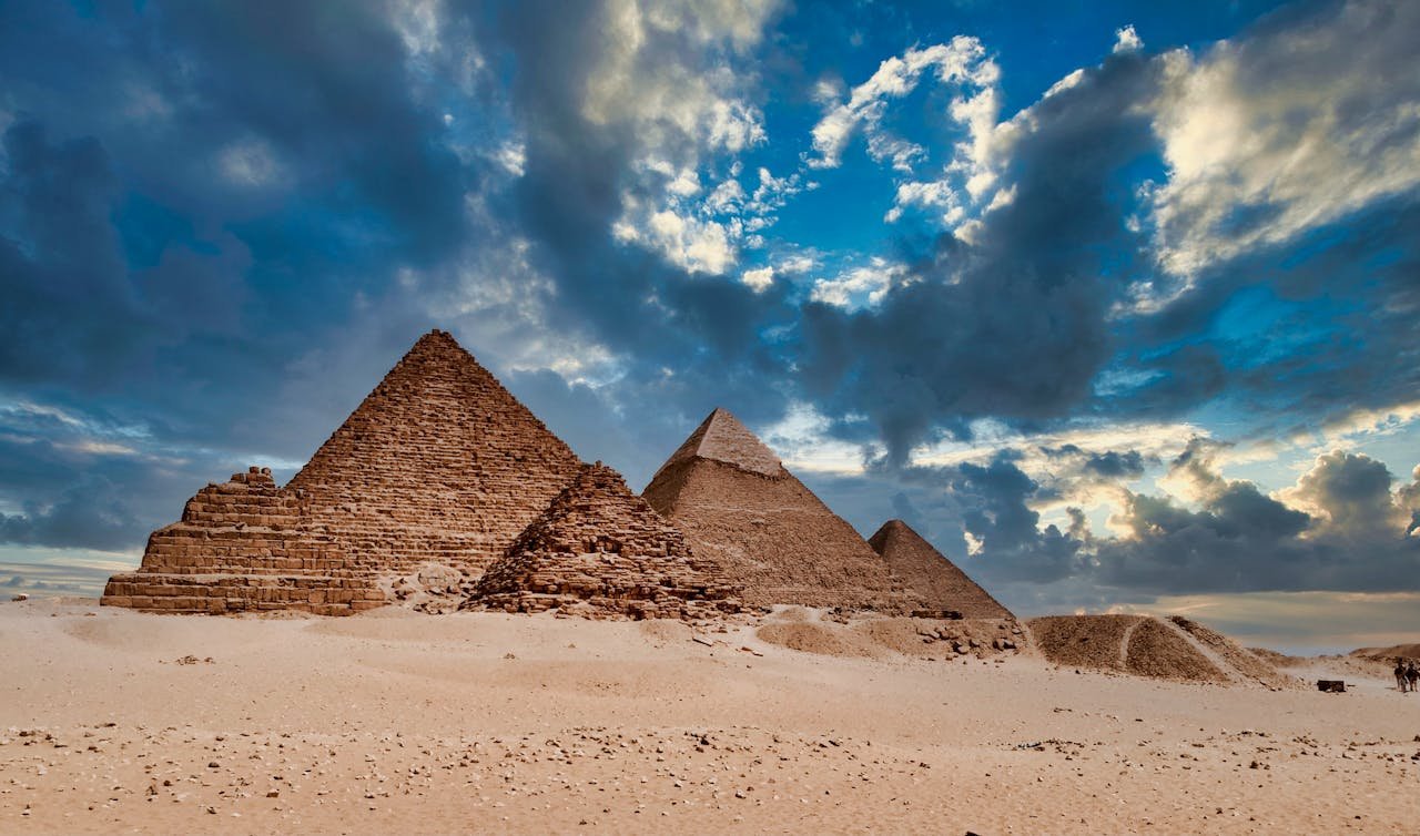 Stunning image of the ancient Giza Pyramids under a dramatic sky at sunset, Egypt.